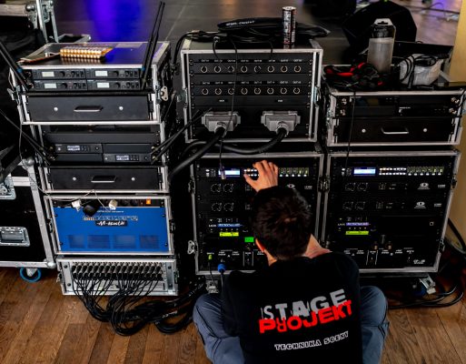 Mężczyzna ustawia parametry na sprzęcie do nagłośnienia przed koncertem.