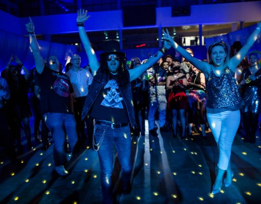 Przebrani za gwiazdy rocka ludzie tańczą i śpiewają na evencie tematycznym.