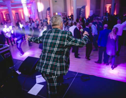 Konferansjer zabawia ze sceny gości na jubileuszu firmowym.