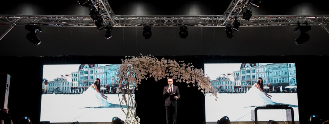 Konferansjer stoi na scenie na targach ślubnych.