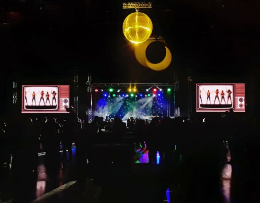 Tłum ludzi bawi się przed sceną na firmowej imprezie integracyjnej.