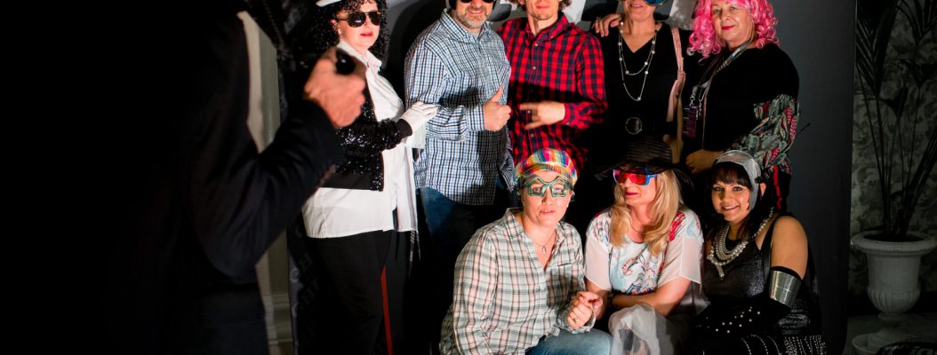 Przebrani ludzie pozują na ściance na imprezie tematycznej.