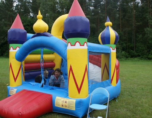 Dziewczynka i chłopiec bawią się w dmuchanym zamku na imprezie dla dzieci.