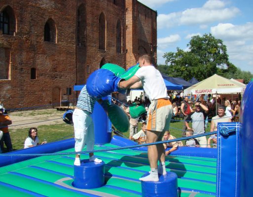 Dwóch mężczyzn toczy pojedynek na dmuchanym ringu bokserskim.