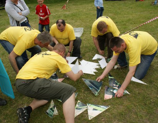 Mężczyźni składają kawałki fotografii na evencie integracyjnym w plenerze.