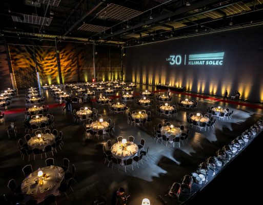 Elegancka sala oświetlona i zaaranżowana na potrzeby bankietu firmowego.