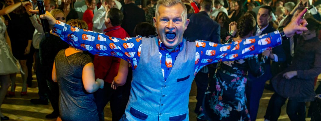 Konferansjer pozuje z mikrofonem na imprezie integracyjnej.