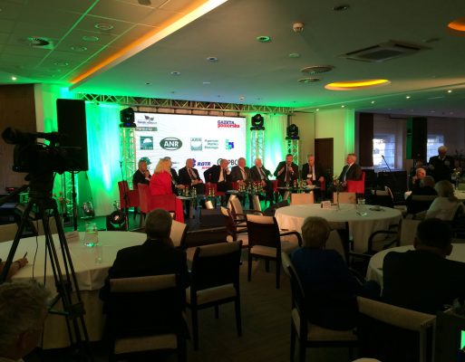 Ludzie siedzą przy stolikach i oglądają debatę w czasie szkolenia.