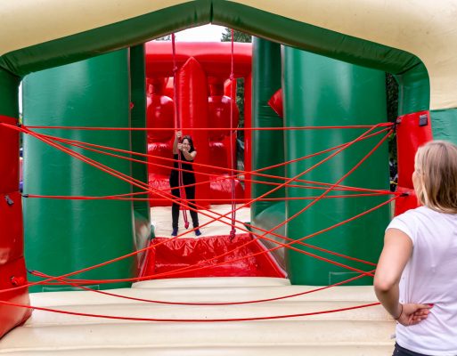 Dwie kobiety ścigają się na dmuchanym torze przeszkód w trakcie eventu integracyjnego.