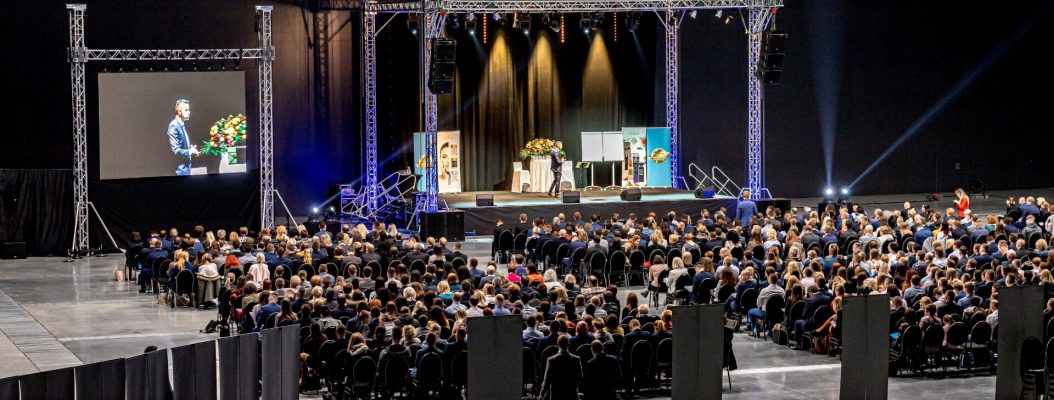 Konferencja zorganizowana dla dużej publiczności w hali targowej.