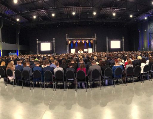 ubliczność siedzi przed konstrukcją sceniczną na konferencji.