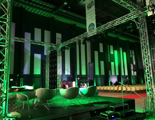 Fotele, sprzęt do nagłośnienia i oświetlenia stoją na scenie w czasie konferencji.