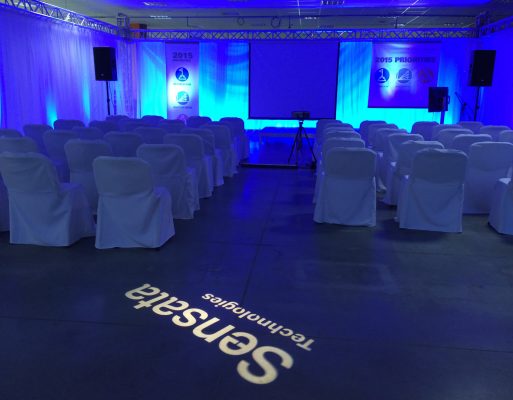 Pusta sala z podestem scenicznym, multimediami i krzesłami zaaranżowana na konferencję firmową.