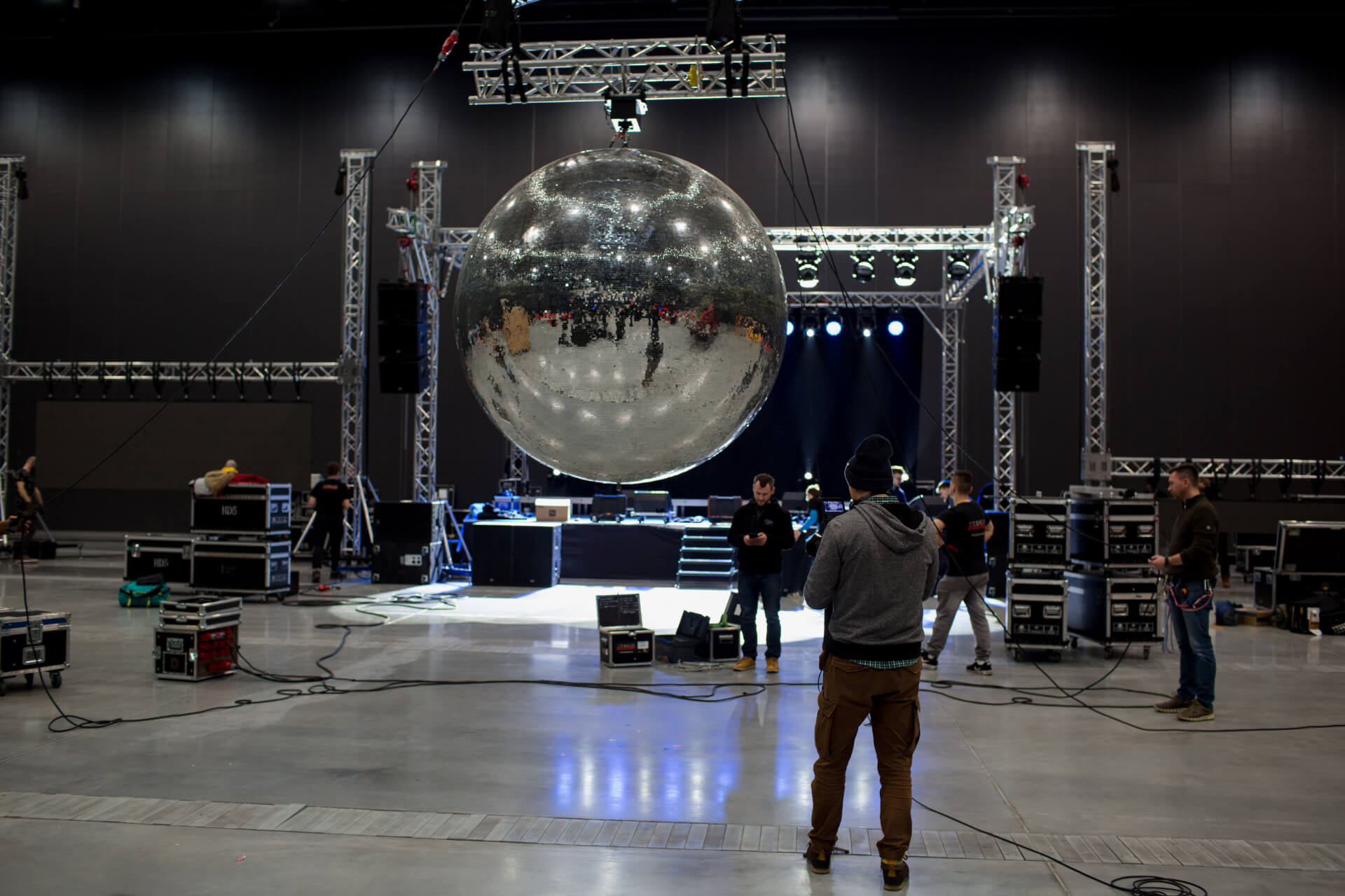 Montaż kuli dyskotekowej na tle sceny w hali przed imprezą firmową w klimacie disco.