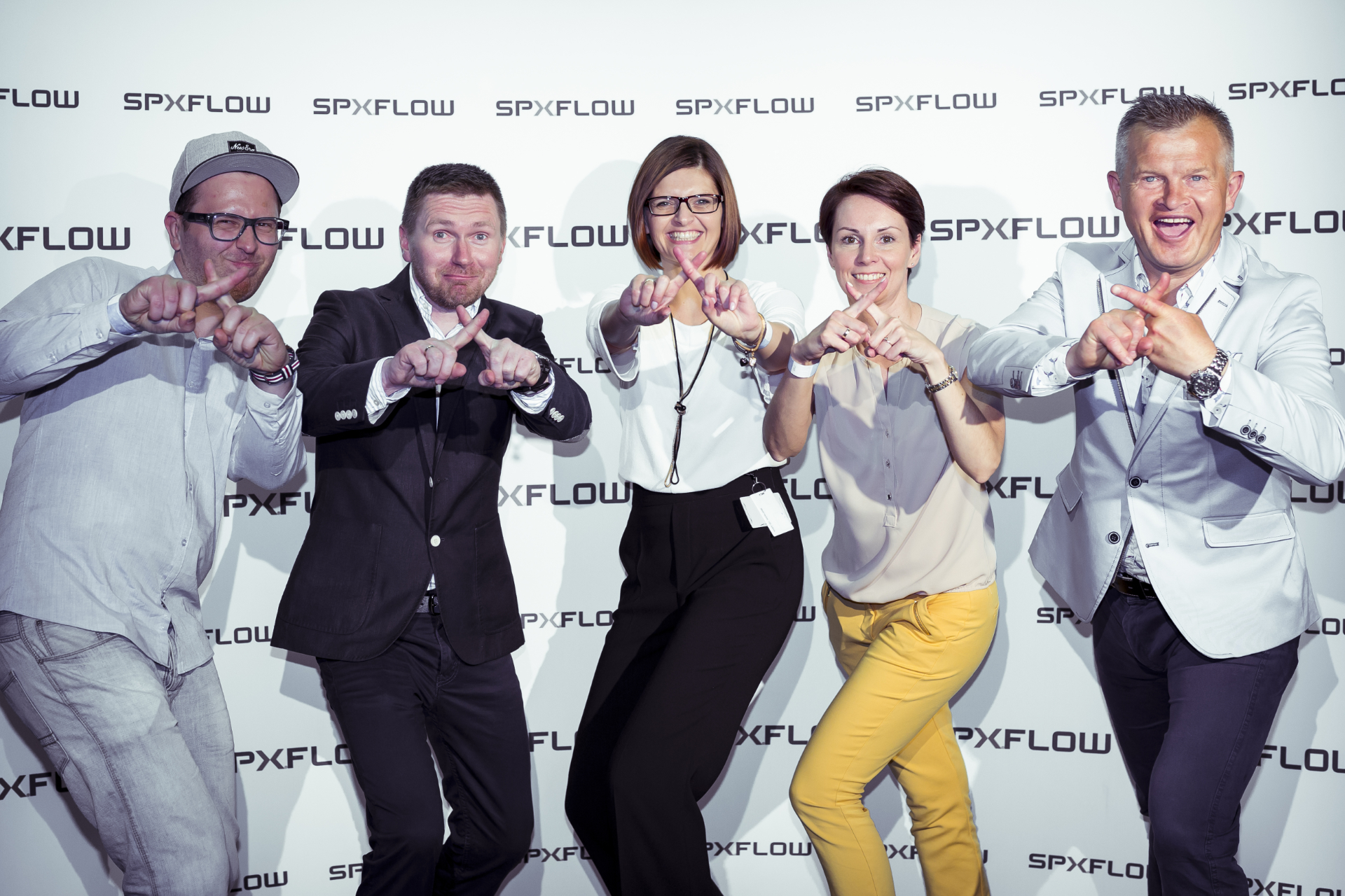 Grupa ludzi pozuje na ściance w trakcie firmowej imprezy integracyjnej.